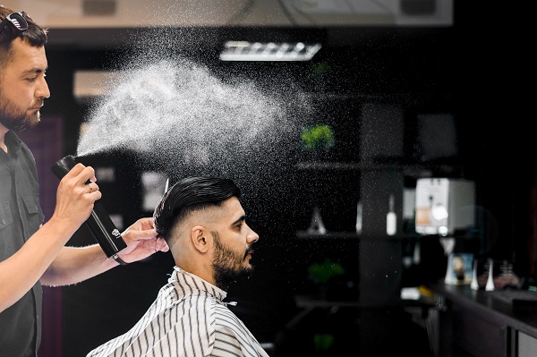 male barber spraying some after shave on customer's hair